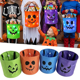 Four children in Halloween costumes holding the light-up trick-or-treat buckets in green, orange, blue and purple